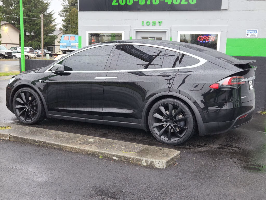 Black Tesla Model X with dark window tint parked outside SC Window Tinting in Puyallup, WA
